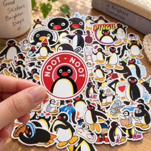 May include: A collection of Pingu stickers featuring various poses of the black and white penguin character. One circular sticker in the foreground displays the text NOOT NOOT in white letters on a red background with an illustration of Pingu.