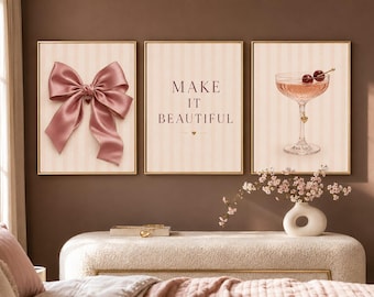 May include: A set of three framed wall art prints with a light pink striped background. The left print features a large dusty pink satin bow. The center print displays the text MAKE IT BEAUTIFUL in dark lettering. The right print shows a cocktail glass.