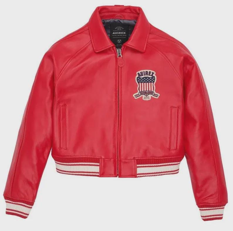 May include: A bright red leather bomber jacket featuring a front zipper closure, a classic collar, and long sleeves. The jacket includes a white and red striped ribbed hem and cuffs, with an embroidered patch on the chest displaying the text AVIREX.