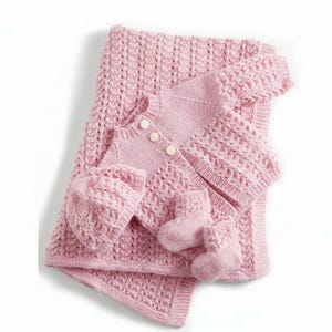 Peut inclure: Un ensemble tricoté pour bébé rose clair comprenant une couverture texturée, un gilet à manches longues avec trois boutons blancs, un bonnet assorti et une paire de petits chaussons. Chaque pièce présente un motif en torsades uniforme.