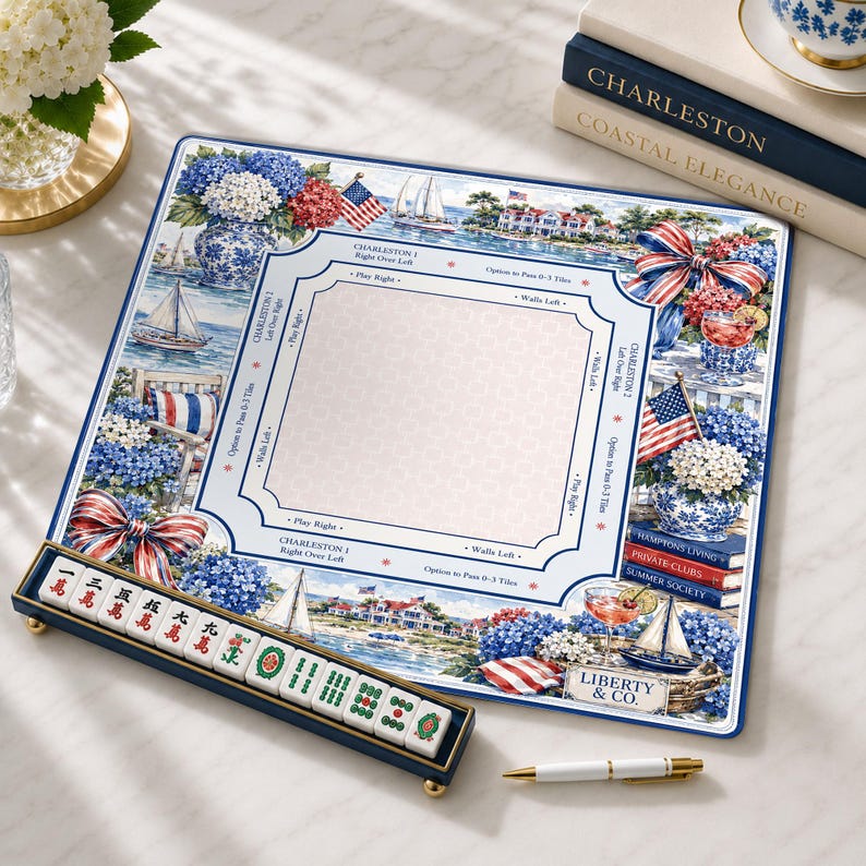 May include: A square mahjong mat featuring a coastal Charleston theme with blue and white hydrangeas, sailboats, American flags, and red-striped bows. It includes a central play area with game instructions, a tile rack with mahjong tiles, and a pen.