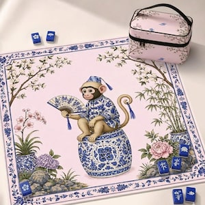 Op de afbeelding: Een vierkante mahjongmat in lichtroze met een centrale illustratie van een aap in een blauw-wit patroonpakje die een waaier vasthoudt en op een keramische kruk zit. Inclusief een bijpassende roze draagtas en speelstenen.