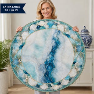 May include: A large circular wall art piece measuring 42 by 42 inches, featuring a central marbled blue and white resin design surrounded by a border of white and blue seashells, pearls, and gold-toned coral accents on a circular frame.