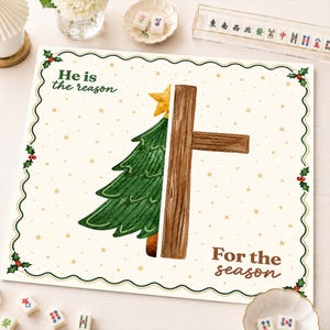 May include: A square decorative sign with a cream background featuring a green Christmas tree on the left and a brown wooden cross on the right. The text reads He is the reason For the season. The border is green with holly and berries.