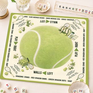 May include: A square mahjong mat featuring a large central tennis ball graphic on a cream background with a green border. The mat includes tennis-themed illustrations, directional arrows, and text instructions for gameplay, including Dragons, Craks, Bams, Dots, and Soap.