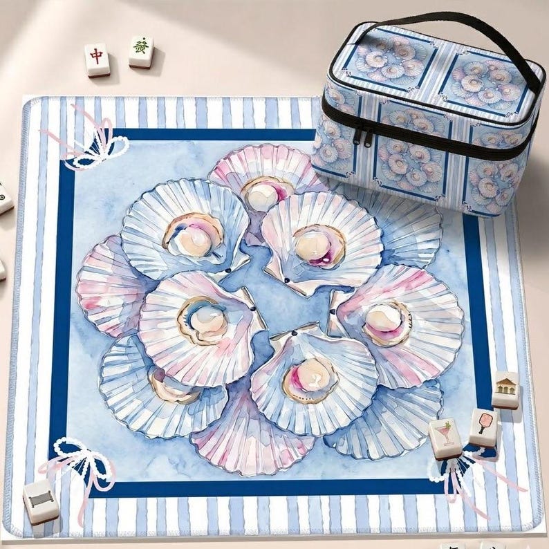 May include: A square mat and a matching rectangular carrying case featuring a watercolor print of white and pink scallop shells with pearls. The design includes a blue and white striped border with white ribbon accents and scattered mahjong tiles.