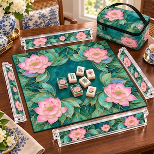 May include: A mahjong set featuring a square play mat, four clear acrylic tile racks, and a zippered carrying case, all decorated with a teal green background and pink lotus flower pattern. Six mahjong tiles are placed in the centre of the mat.