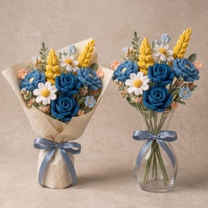 May include: Two arrangements of crocheted flowers featuring deep blue roses, white daisies, yellow lupines, and small light blue and peach blossoms. One bouquet is wrapped in textured beige paper with a blue ribbon, the other sits in a glass vase.