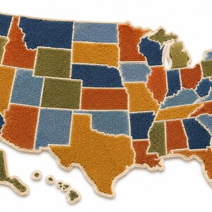 May include: A tufted rug shaped like the map of the United States, including Alaska and Hawaii. The individual states are rendered in a palette of blue, orange, yellow, and olive green, with each state outlined by a thick, cream-colored border.