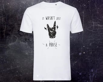 May include: A white short-sleeved t-shirt featuring a black graphic of a hand making a rock and roll sign. The text above the hand reads IT WASN'T JUST and the text below the hand reads A PHASE. The design includes small lightning bolt accents.