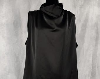 May include: A sleeveless black top featuring a high cowl neckline and a smooth, satin-like finish. The garment is displayed on a mannequin, showcasing a draped, loose-fitting silhouette that falls straight from the shoulders to the hemline.