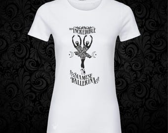 May include: A white short-sleeved t-shirt featuring a black graphic print of a conjoined ballerina figure. The text above reads THE INCREDIBLE and the text below reads SIAMESE BALLERINA, accompanied by small crescent moon and star symbols.