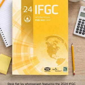 May include: The 2024 IFGC International Fuel Gas Code book features a yellow cover with white text, a globe graphic, and logos for PHCC, AGA, and ICC. The book is positioned on a desk surrounded by office supplies including a pen, pencil, and calculator.