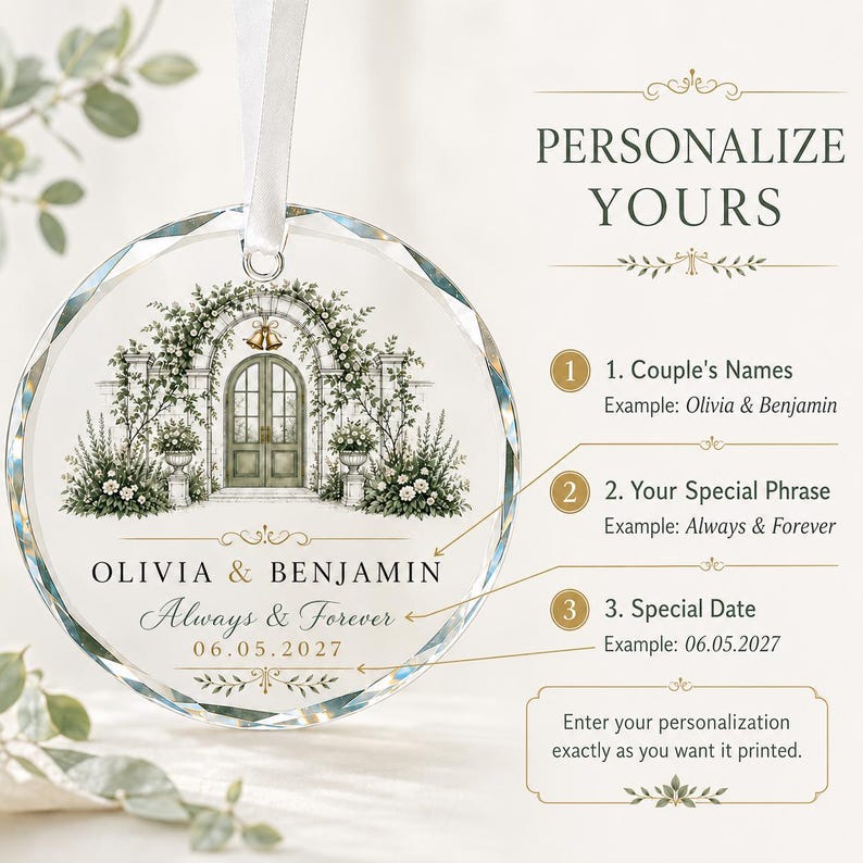 Puede incluir: Un adorno de cristal redondo y facetado con una ilustraci&oacute;n impresa de un arco de jard&iacute;n con campanas y arreglos florales. El texto dice OLIVIA & BENJAMIN, Always & Forever y 06.05.2027. Incluye una cinta blanca para colgarlo.