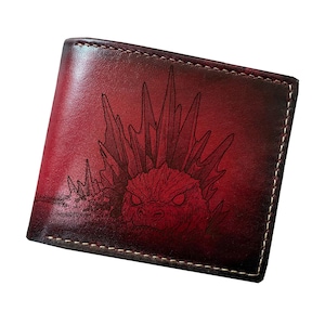 May include: A bi-fold leather wallet in a deep red and black gradient finish. The front features a detailed laser-engraved illustration of a spiky, reptilian monster with glowing eyes. The wallet is constructed with visible light-colored stitching.