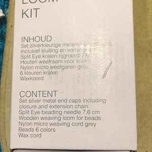 Może przedstawiać: Białe pudełko z napisem "WEAVING LOOM KIT" i listą zawartości. Zestaw zawiera srebrne metalowe końc&oacute;wki, igłę do nawlekania koralik&oacute;w 7,6 cm, drewniane krosno, nić nylonową, koraliki i sznurek woskowy.