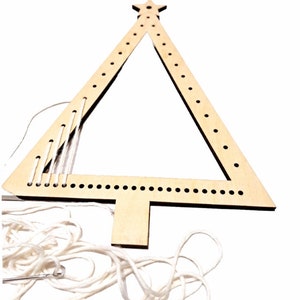 Puede incluir: Un marco de madera con forma de &aacute;rbol de Navidad con agujeros para enhebrar hilo. El marco es de color marr&oacute;n claro y tiene una estrella en la parte superior. Se incluye hilo blanco y una aguja.
