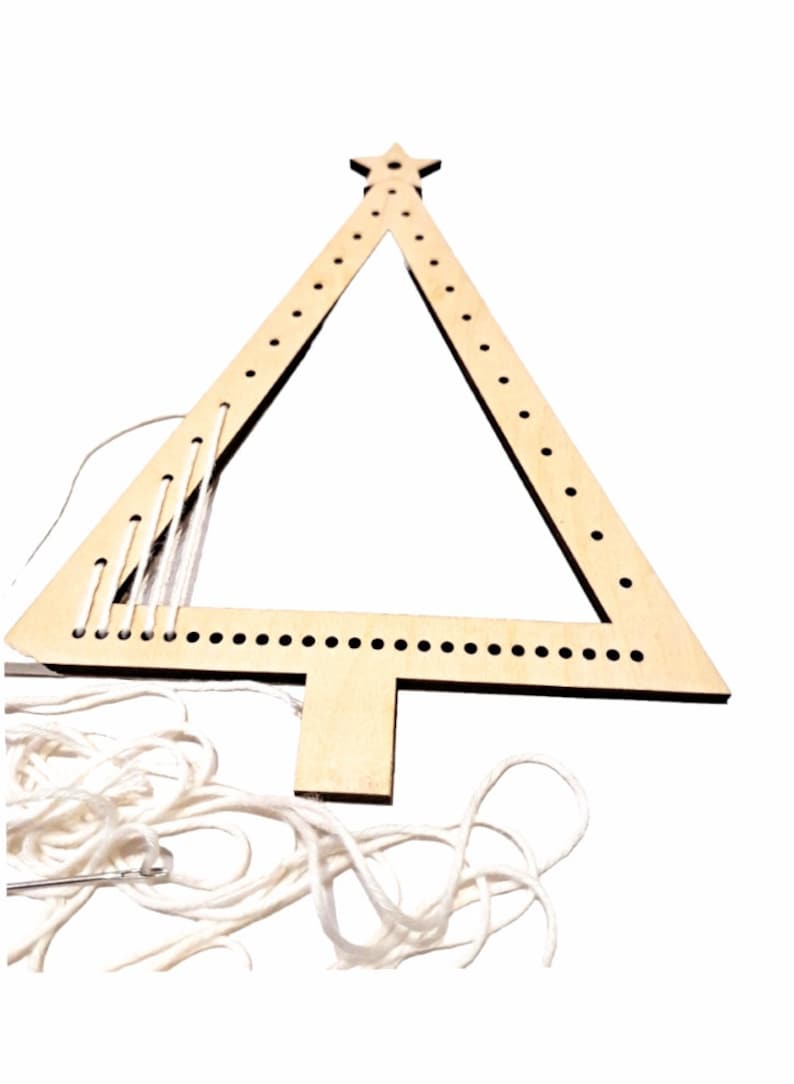 Puede incluir: Un marco de madera con forma de &aacute;rbol de Navidad con agujeros para enhebrar hilo. El marco es de color marr&oacute;n claro y tiene una estrella en la parte superior. Se incluye hilo blanco y una aguja.