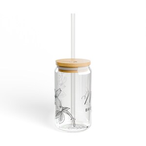 Könnte beinhalten: Ein Trinkglas aus klarem Glas mit einem Bambusdeckel und einem geraden Glasstrohhalm. Die Außenseite ist mit einer schwarzen Strichzeichnung eines Blumenastes und dem Teiltext "BRIDE" in einer klaren, serifenlosen Schrift versehen.