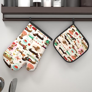 May include: An oven mitt and a square pot holder featuring a repeating pattern of brown dachshund dogs, pink roses, and teal flowers on a cream background. The text "I love dachshund" is printed in small black letters throughout the fabric design.