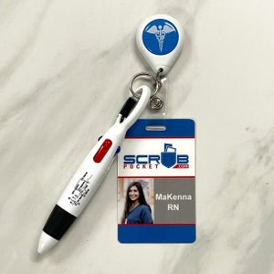 May include: A white retractable badge holder with a blue medical symbol, attached to a black and white pen with a red accent. The badge holder is attached to a white ID card with the text "SCRUB POCKET.com" and a photo of a woman with the name "Makenna RN".