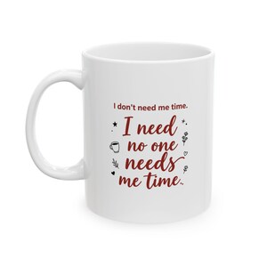 Könnte beinhalten: Ein weißer Keramikbecher mit dem dunkelroten Text I don't need me time. I need no one needs me time. Das Design enthält kleine schwarze grafische Symbole einer Kaffeetasse, eines Herzens und floraler Zweige, die um den Text angeordnet sind.