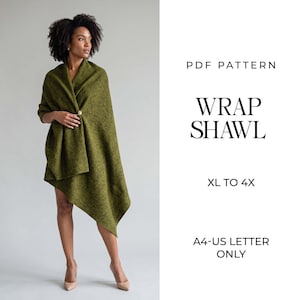 May include: A PDF pattern for a wrap shawl in sizes XL to 4X, formatted for A4 and US letter paper. The image displays a textured olive green wrap shawl secured with a single gold-toned pin, featuring an asymmetrical hemline and draped fabric.