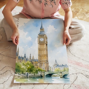 Könnte beinhalten: Ein Aquarellgemälde auf Papier, das den Elizabeth Tower, bekannt als Big Ben, in London darstellt. Das Kunstwerk zeigt den ikonischen Uhrturm in Gold- und Brauntönen vor einem hellblauen Himmel mit grünen Bäumen und einer Brücke.