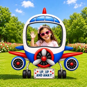 Pode incluir: Um acessório de cabine de fotos em forma de avião branco, azul e vermelho com um recorte central para rostos, uma hélice frontal e uma placa retangular na base com o texto UP, UP AND AWAY! cercado por pequenas estrelas vermelhas.