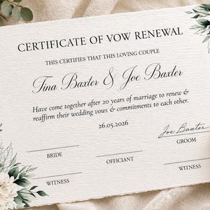 May include: A white paper certificate of vow renewal with deckled edges, featuring black text and green floral illustrations in the corners. The document includes the names Tina Baxter and Joe Baxter, the date 26.05.2026, and signature lines.