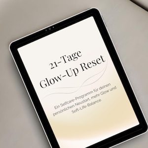 Könnte beinhalten: Ein Tablet mit dem Text "happyweekend" am oberen Rand, gefolgt von "21-Tage Glow-Up Reset" und "Ein Selfcare-Programm für deinen persönlichen Neustart, mehr Glow und Soft-Life-Balance." Der Bildschirm hat einen Farbverlauf von Weiß zu Beige.