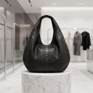May include: A black hobo bag featuring a textured snakeskin pattern. The bag has a single integrated handle, a curved silhouette, and a deep, rounded base. The material displays a consistent scale-like surface throughout the entire exterior.