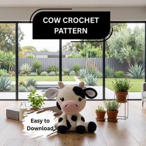 May include: A white and black crocheted cow plush toy with a pink snout and black eyes. The image features the text COW CROCHET PATTERN at the top and Easy to Download at the bottom left. The toy is positioned on a wooden floor in a room.