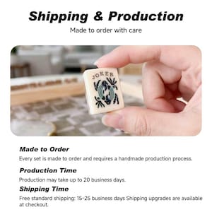 May include: A rectangular off-white mahjong tile featuring the word JOKER printed in black at the top, with a central graphic illustration of two stylized fish in shades of blue and green, surrounded by small black leaf-like decorative accents.