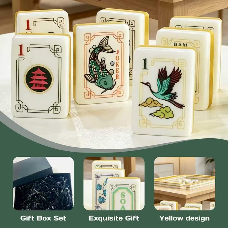 May include: A set of rectangular Mahjong tiles featuring white surfaces with gold edges and various colorful illustrations including a red pagoda, a green koi fish labeled Joker, and a crane. The set includes a black gift box with black filler.