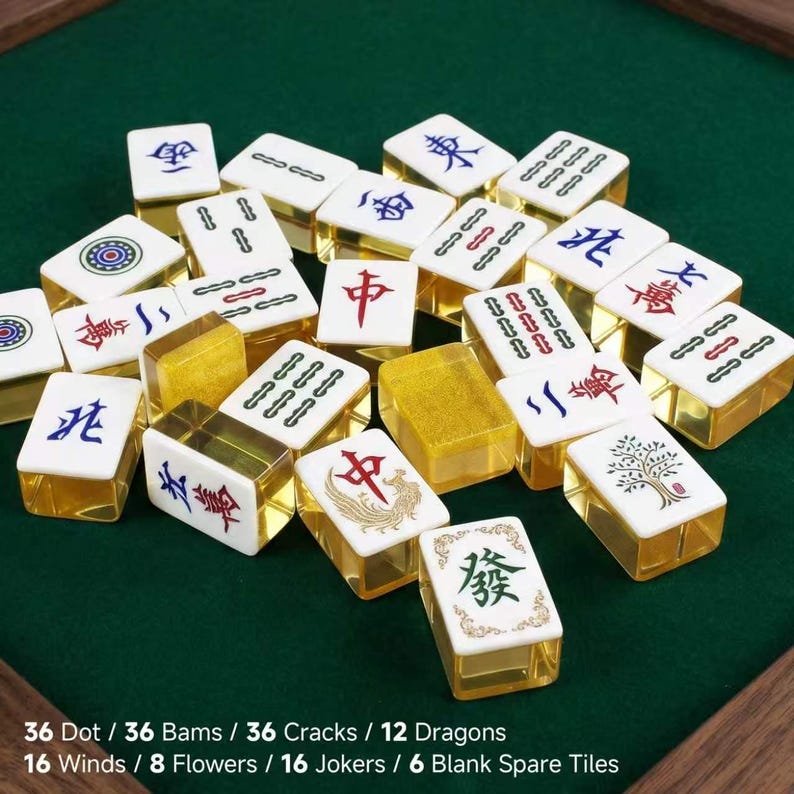 May include: A collection of Mahjong tiles with white faces and translucent yellow backs. The tiles feature various colorful Chinese characters, symbols, and floral designs. Text at the bottom lists: 36 Dot, 36 Bams, 36 Cracks, 12 Dragons, 16 Winds, 8 Flowers, 16 Jokers, 6 Blank Spare Tiles.