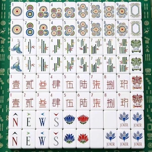 May include: A complete set of white mahjong tiles arranged in a grid. The tiles feature colorful circular patterns, green bamboo stalks, Chinese characters, directional letters N, E, W, S, lotus flowers, and joker tiles with blue floral designs.