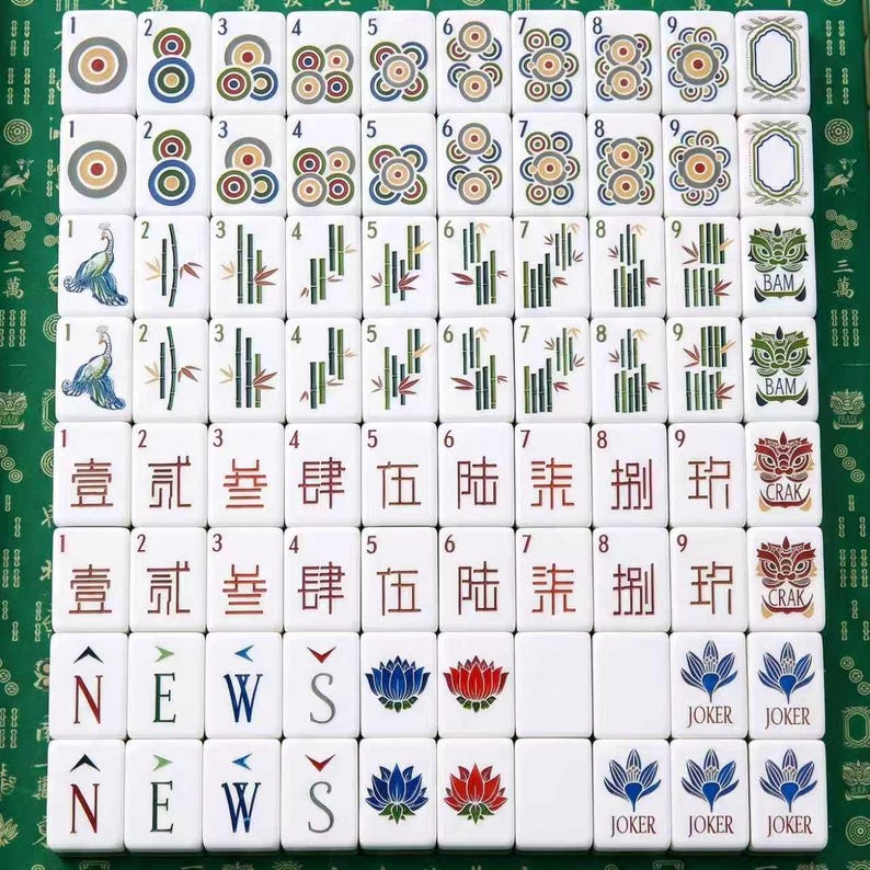 May include: A complete set of white mahjong tiles arranged in a grid. The tiles feature colorful circular patterns, green bamboo stalks, Chinese characters, directional letters N, E, W, S, lotus flowers, and joker tiles with blue floral designs.