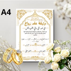 Peut inclure: Un document de contrat de mariage islamique au format A4 avec des bordures dorées ornées et une calligraphie arabe. Le certificat comprend des lignes vides pour les noms et les dates, accompagné de deux alliances dorées et de roses blanches.