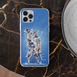 May include: A clear phone case featuring a blue graphic design of a soccer player in a white jersey. The design includes multiple poses of the athlete and the text "JUDE BELLINGHAM" in a stylized font. The case has a cutout for the camera lens.