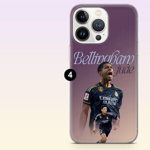 May include: A purple smartphone case featuring a graphic of soccer player Jude Bellingham in a dark blue jersey. The design includes the text Bellingham and jude in a stylized font. The case has a cutout for a triple-lens camera system on the back.