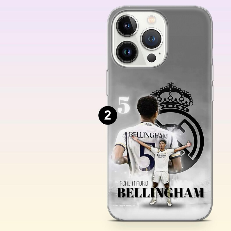 May include: A smartphone case featuring a graphic of Jude Bellingham in a white Real Madrid kit. The design includes the number 5, the Real Madrid crest, and the text 'REAL MADRID BELLINGHAM' in black and white tones on a grey background.