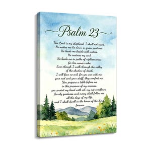 Op de afbeelding: Een rechthoekig canvas wandkunstwerk met een aquarel landschap van groene heuvels, bomen en verre bergen onder een blauwe lucht. De tekst Psalm 23 en het volledige bijbelgedeelte zijn in zwarte letters in het midden van het beeld gedrukt.