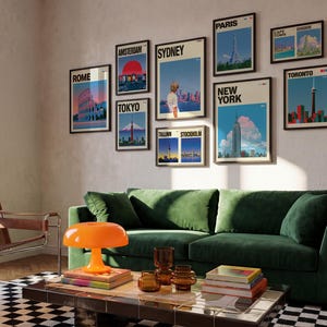May include: A gallery wall featuring nine framed travel posters depicting cities including Rome, Amsterdam, Tokyo, Sydney, Paris, New York, Tallinn, Stockholm, Cape Town, Bangkok, and Toronto, displayed above a green velvet sofa and coffee table.