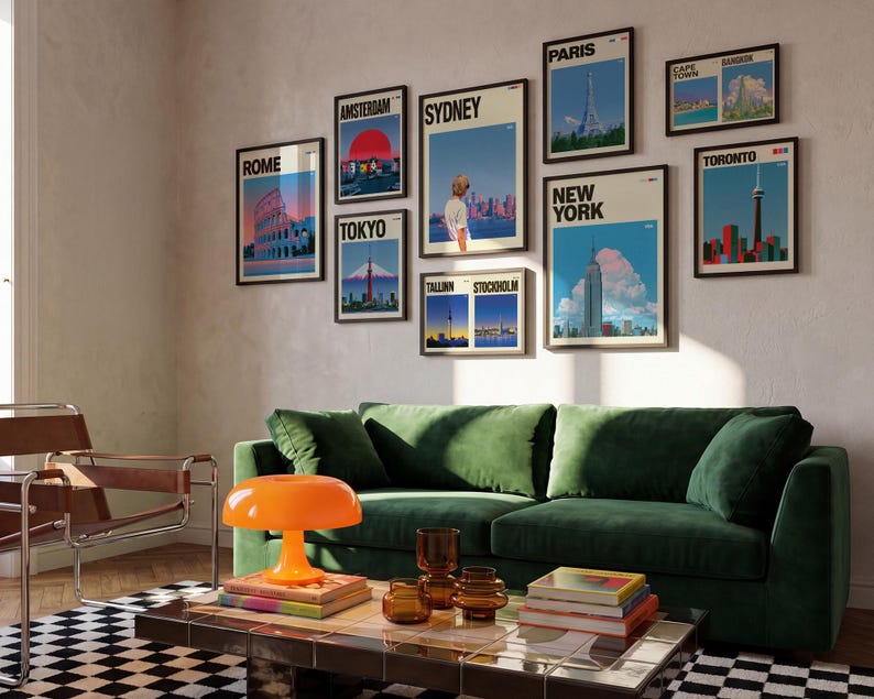 May include: A gallery wall featuring nine framed travel posters depicting cities including Rome, Amsterdam, Tokyo, Sydney, Paris, New York, Tallinn, Stockholm, Cape Town, Bangkok, and Toronto, displayed above a green velvet sofa and coffee table.
