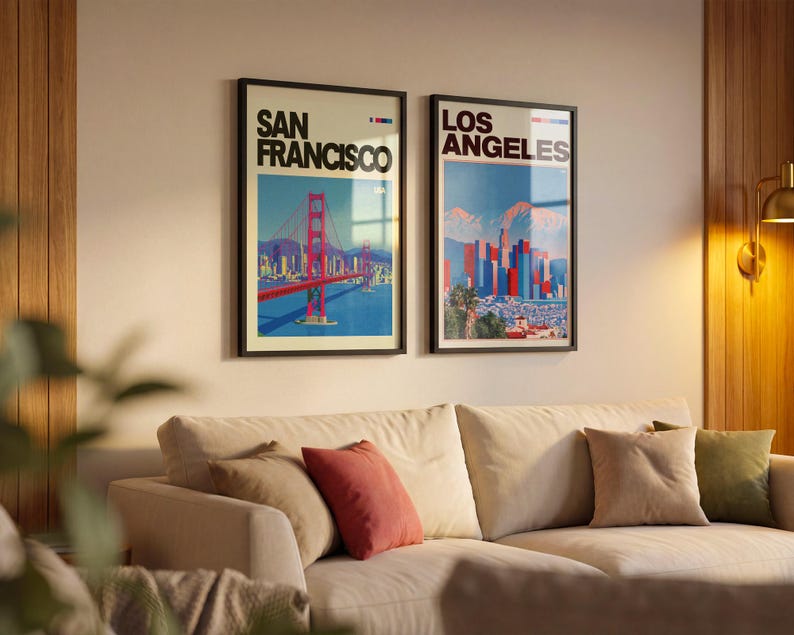 May include: Two framed vertical wall art prints featuring cityscapes. The left print displays the Golden Gate Bridge with the text San Francisco. The right print shows the Los Angeles skyline with mountains and the text Los Angeles in black font.