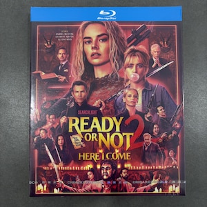 May include: A Blu-ray disc case featuring the movie poster for Ready or Not 2: Here I Come. The artwork displays a collage of various characters in a dark, red-toned setting, with the title text prominently centered in yellow and red lettering.
