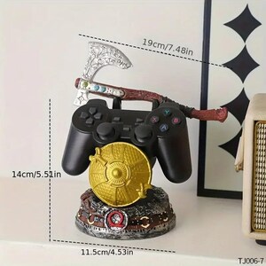 Peut inclure: Un support de manette de jeu vid&eacute;o noir avec une hache argent&eacute;e aux gravures florales, un bouclier circulaire dor&eacute; et une base orn&eacute;e d'un symbole Omega rouge. Le support mesure 19 cm de large, 14 cm de haut et 11,5 cm de profondeur, mod&egrave;le TJ006-7.