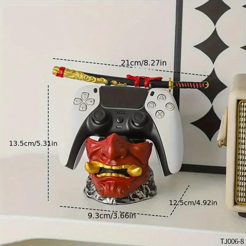 Peut inclure: Un support de manette en forme de masque oni rouge et dor&eacute;, surmont&eacute; d'une manette de jeu noire et blanche, avec un katana d&eacute;coratif plac&eacute; horizontalement &agrave; l'arri&egrave;re. Le support mesure 9,3 cm sur 12,5 cm sur 13,5 cm, avec un sabre de 21 cm.