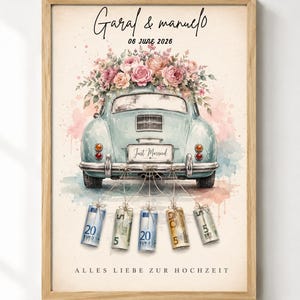 May include: A framed print featuring a light blue vintage car with a floral arrangement on the roof, a 'Just Married' license plate, and five rolled-up Euro banknotes tied to the bumper. The text reads 'Garal & manuel', '06 JUNE 2026', and 'ALLES LIEBE ZUR HOCHZEIT'.